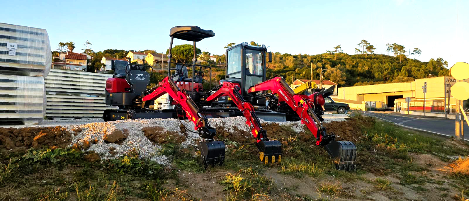 Three LANDWARD mini excavators with buckets displayed outdoors