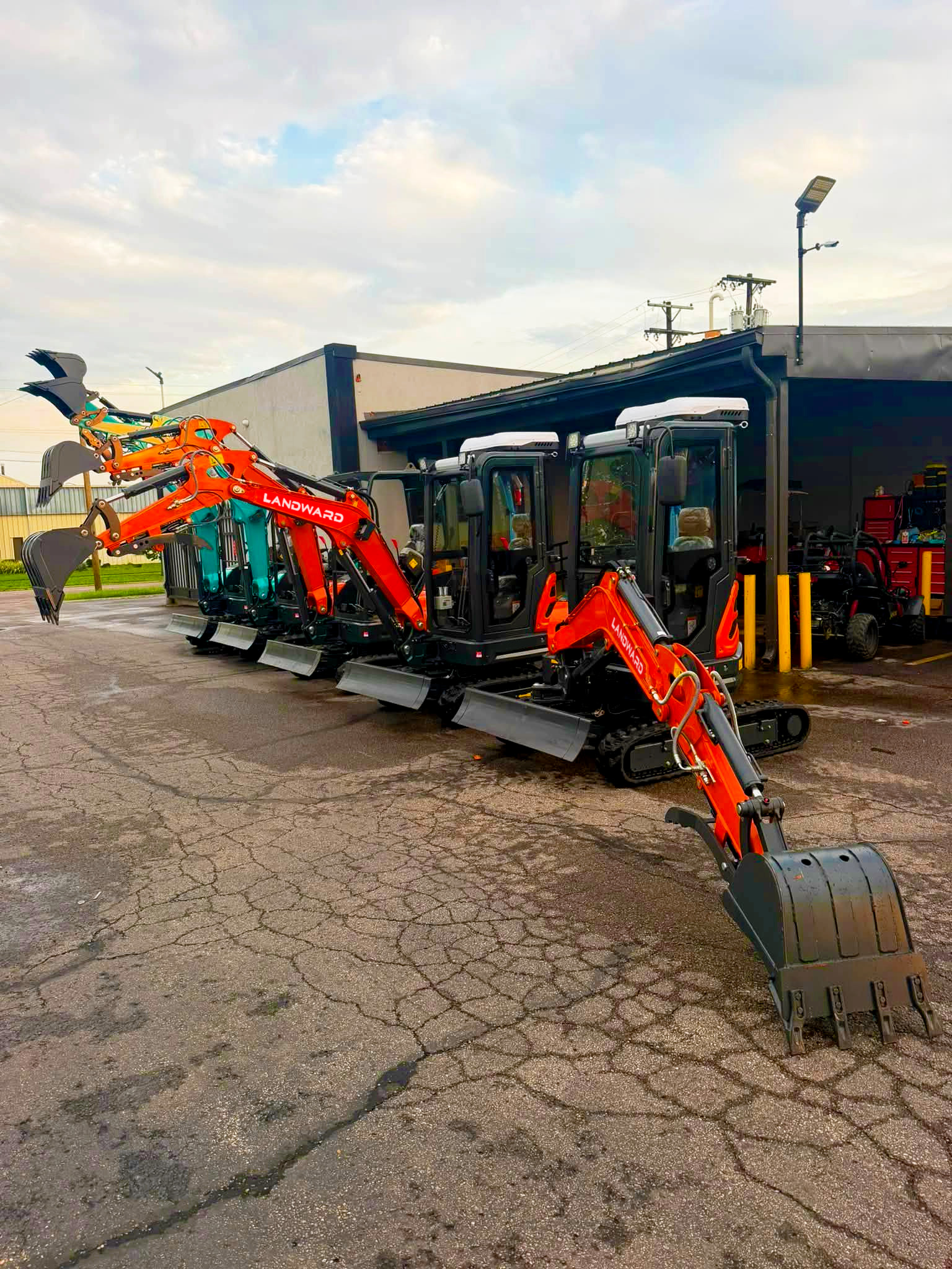 LANDWARD mini excavators with buckets and grapples outside a workshop